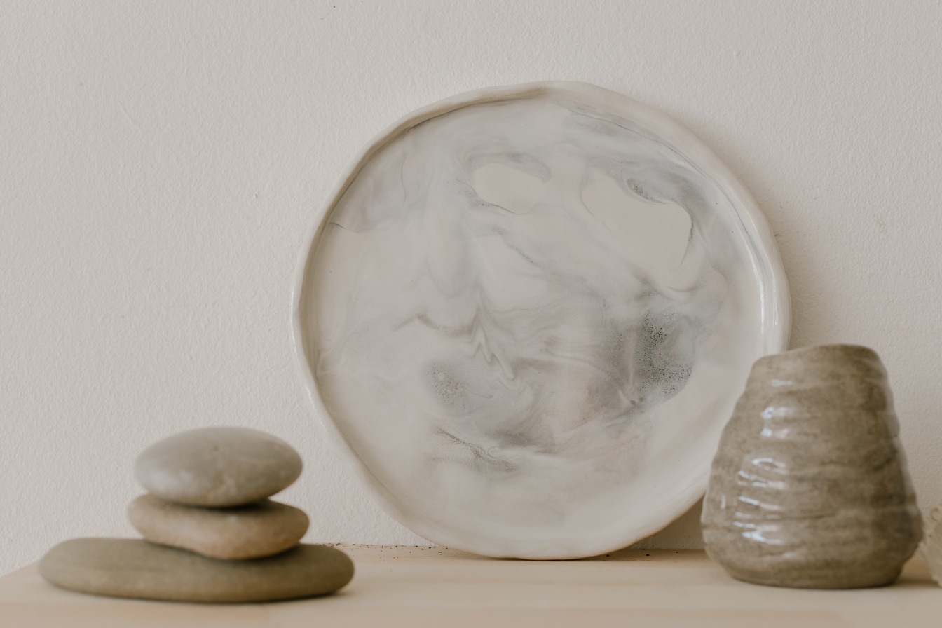 White Round Ceramic Plate With Brown Vase and Stones on Table